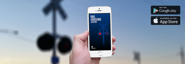 Close up ng smartphone na nagpapakita ng Rail Crossing Locator. Ang background ay isang malabong larawan ng isang tawiran ng riles.