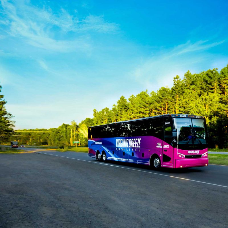 Virginia Breeze bus sa interstate. Asul na langit at evergreen na mga puno.