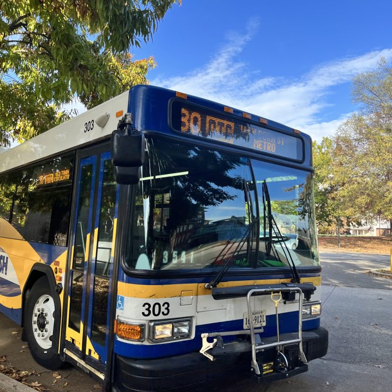 Isang photographic na larawan ng isang pampublikong bus na nakaparada sa tabi ng isang tahimik na kalye.
